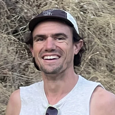 Brandon Costa smiling in a cap outdoors.